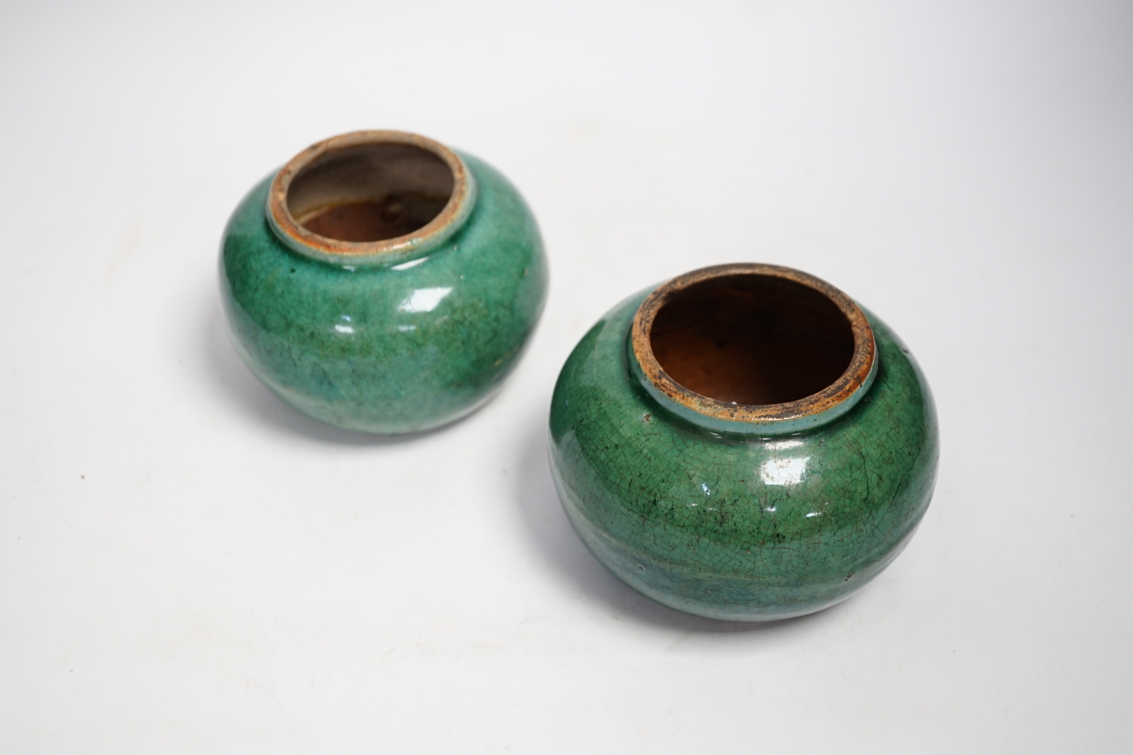 A pair of Chinese pottery monochrome green glazed jars, 10cm high